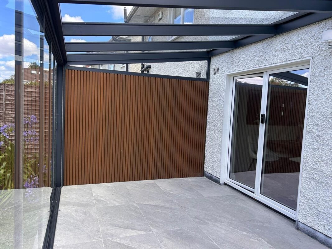 Side enclosure with a composite cladding wall and frameless sliding glass