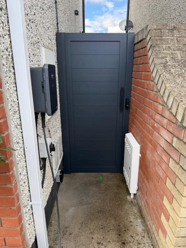 Anthracite aluminium side gate in a narrow side passage beside a brick wall